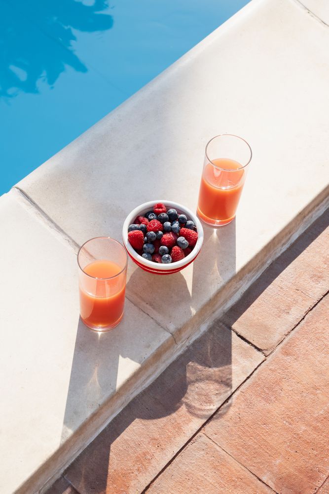 Healthy summer breakfast with fresh berries and juice by the swimming pool