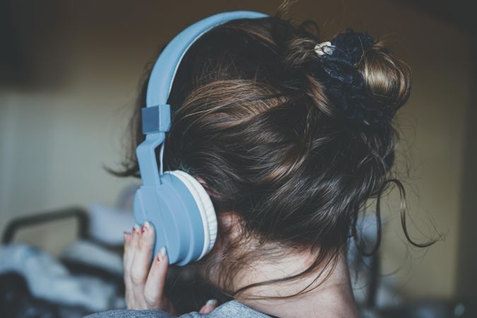 Back view of young woman wearing blue headphone