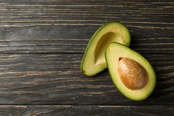 Ripe fresh avocado on wooden background, top view