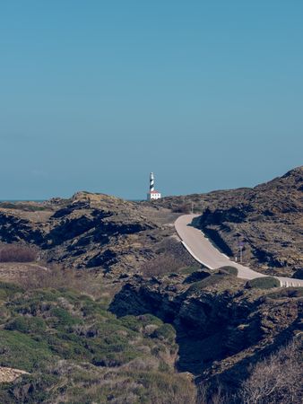 Lighthouse on top of mountain and asphalt roadway among rocks