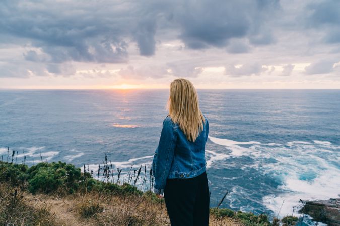 Woman on seashore against dusky clouds