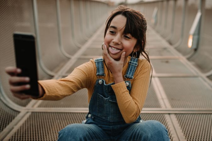 Funny girl taking selfie on smartphone on walkway
