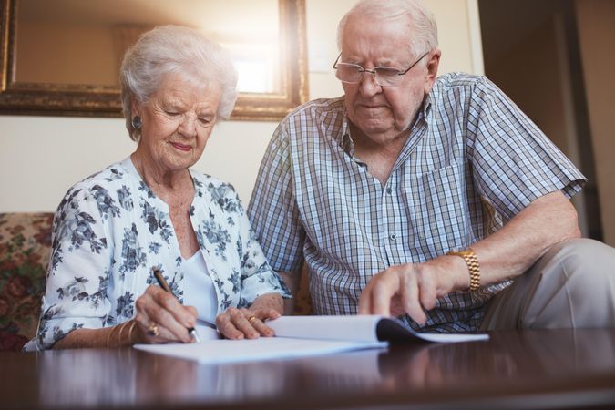 Indoor shot of mature couple at home signing documents together