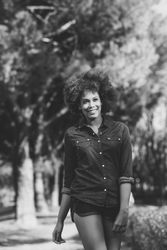 B&W shot of happy with afro walking tall through park on sunny day