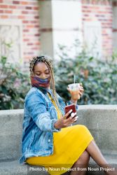 Woman sitting in front of library wearing mask taking a selfie and holding iced coffee 41lop5