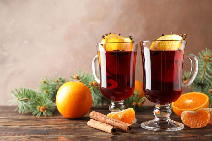 Glasses of tasty mulled wine with orange on wooden background, space for text