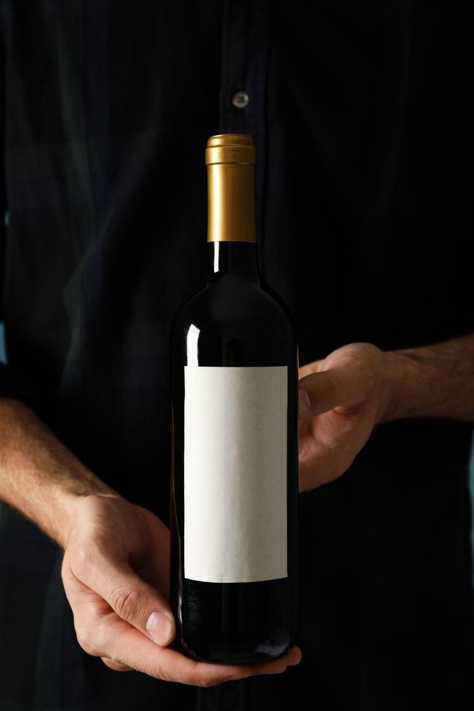 Man in shirt hold bottle of wine with empty space