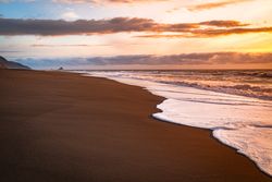 Frothy waves coming in on a quiet beach at sunset