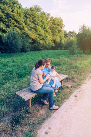 Woman feeding to baby girl sitting in a bench