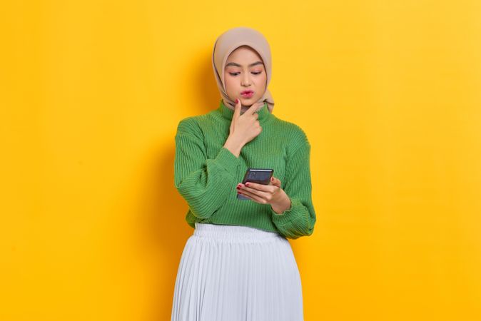 Woman in headscarf reading something interesting on smart phone