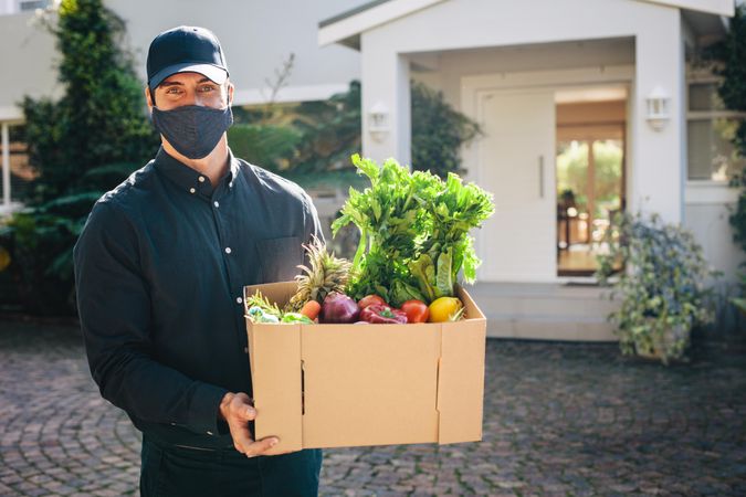 Male courier worker delivering groceries ordered online during pandemic
