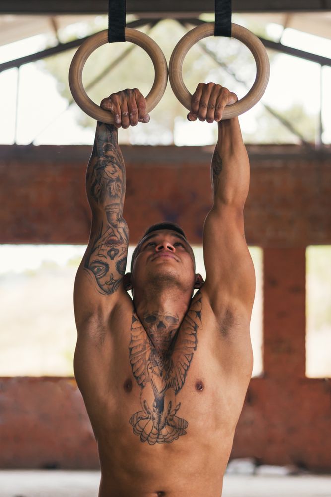 man athlete doing pull ups in gymnastic rings
