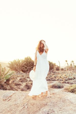 Woman in white dress in dry field in sunlight