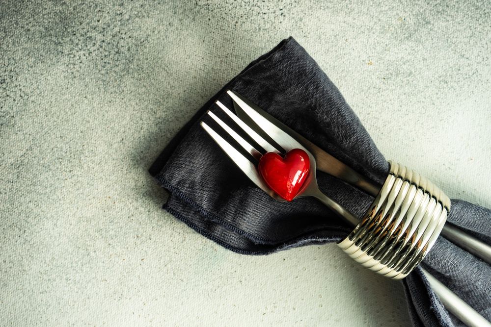 St. Valentine day card with napkin, silverware and heart decorations on grey counter