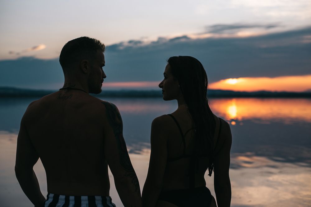 Couple hugging on beach of lake at sunset