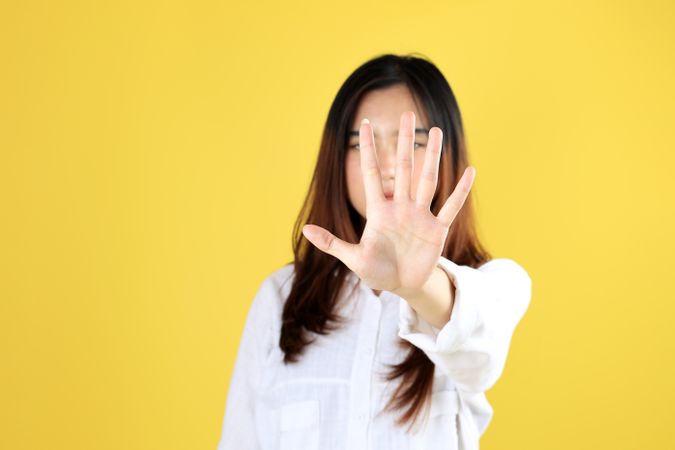 Serious Young Woman Showing Stop Gesture with Her Palm in Front of Face