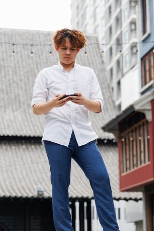 Asian man playing on mobile phone standing in the city
