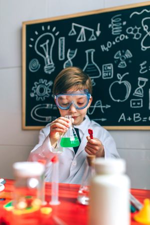 Boy in safety glasses playing with chemistry game