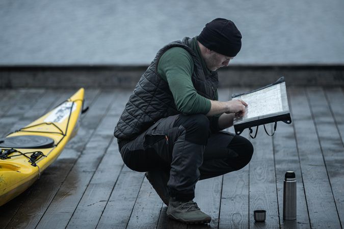 Man reading notes beside a yellow kayak