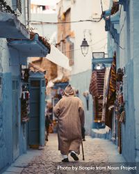 Back view of Moroccan man in djellaba with hood walking in the alley of Chefchaouen, Morocco 428a10