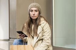 Female sitting outdoors while using a phone