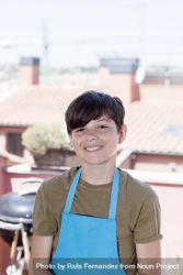 Portrait of smiling teenager standing on terrace wearing a gardener apron 5oD1aG