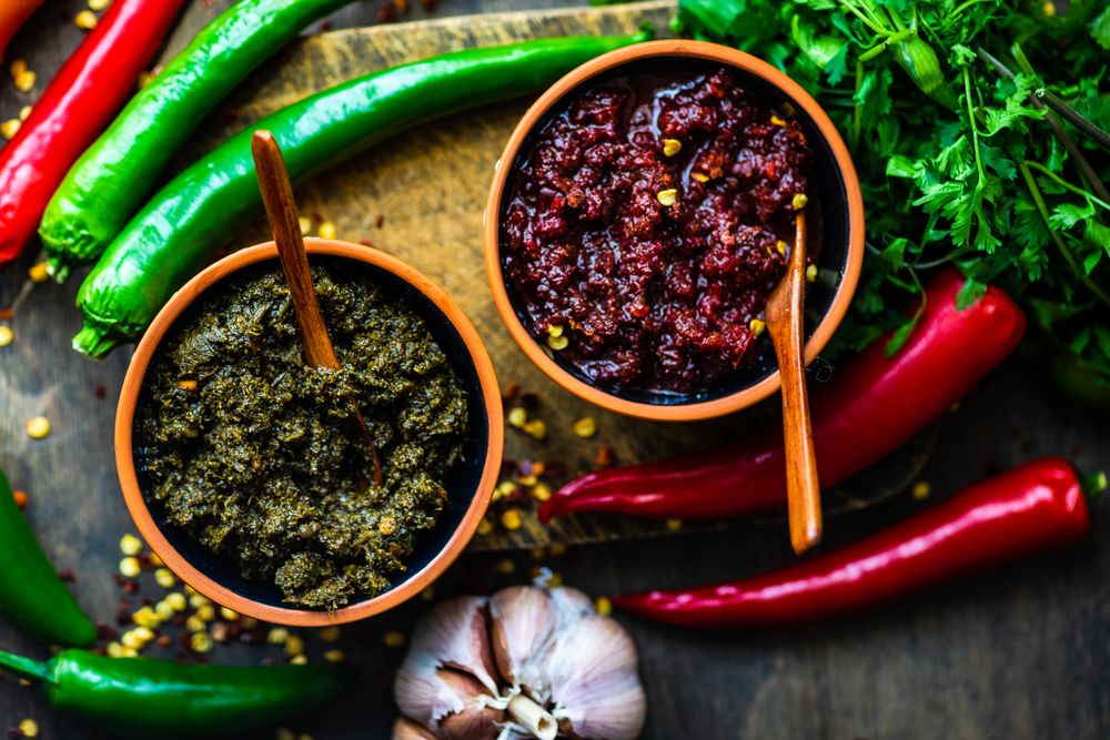 Top view of pots of traditional Georgian sauce Adjika with garlic bulb