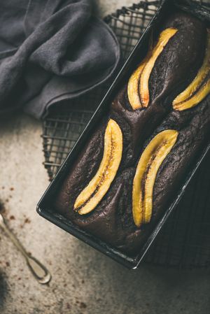 Freshly baked dark chocolate banana bread cake on concrete counter, vertical composition