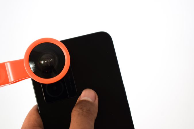 Hand holding smartphone with snap on lens