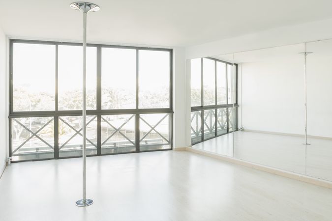 Pole dance studio with big mirrors and windows in light room