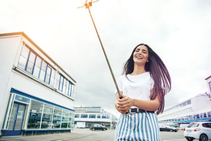 Smiling woman in street with selfie stick