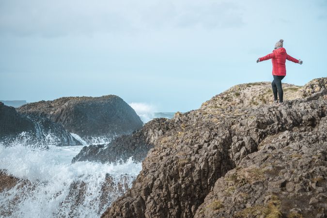 Woman on top of rock with sea surf