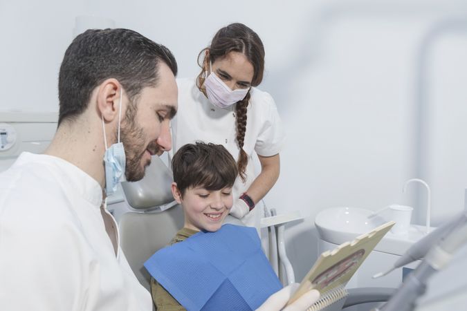 A portrait of a dentist explaining procedure to his smiling teenage patient