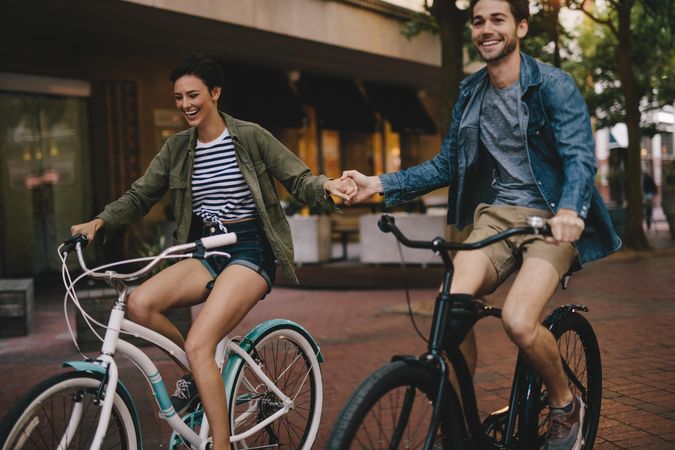 Happy couple holding hands and riding on bikes