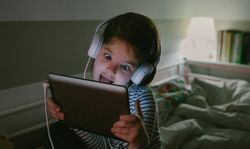 Girl grimacing with headphones looking at the tablet
