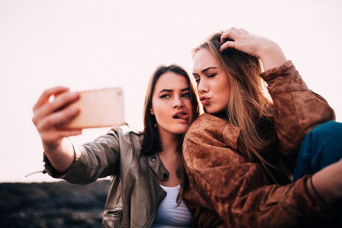 Two young women taking a silly selfie outside