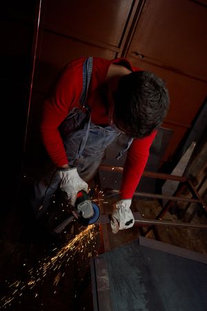 Master cutting metal plank by angle grinder