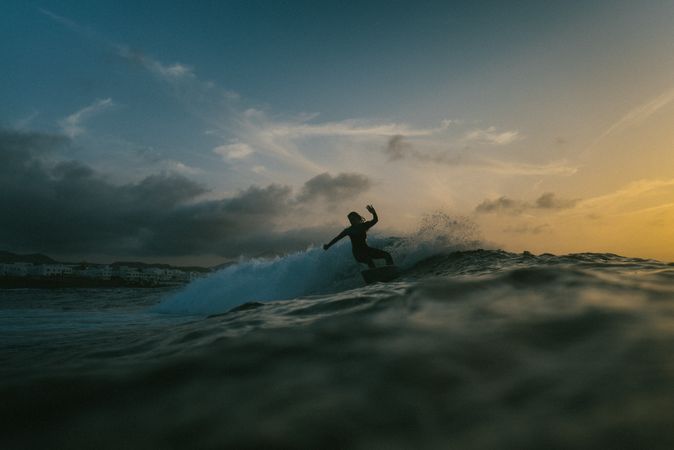 Silhouette of surfer riding a wave at dusk
