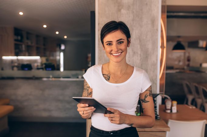 Portrait of a smiling coffee shop owner standing inside her shop