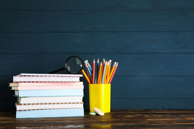 Composition with school supplies on wood table against dark background