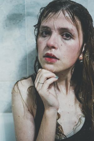 Portrait of wet woman against tile wall