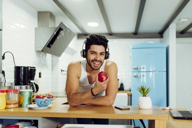 Young happy man in headphones holding apple