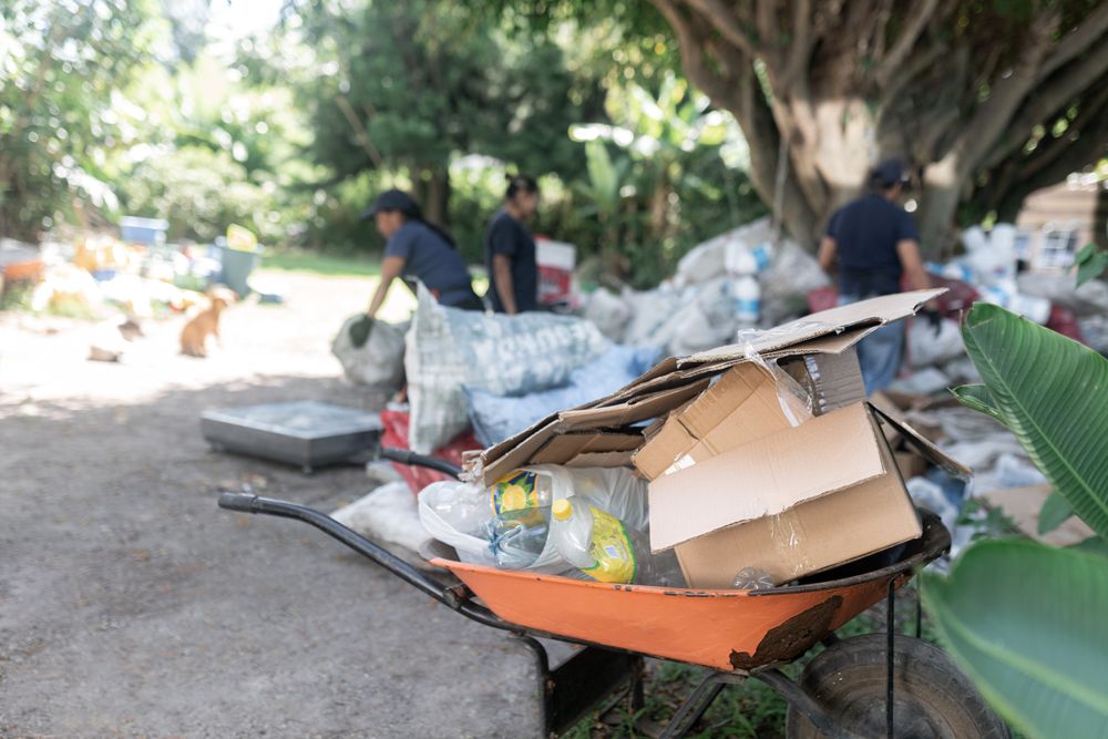 Packed Wheelbarrow of Plastics and Cardboard with Background Workers