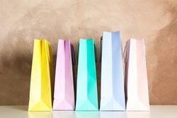 Color bags on table against brown background, copy space