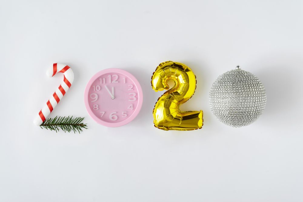 2020 spelled with different decorative objects; candy cane, clock, balloon and disco ball