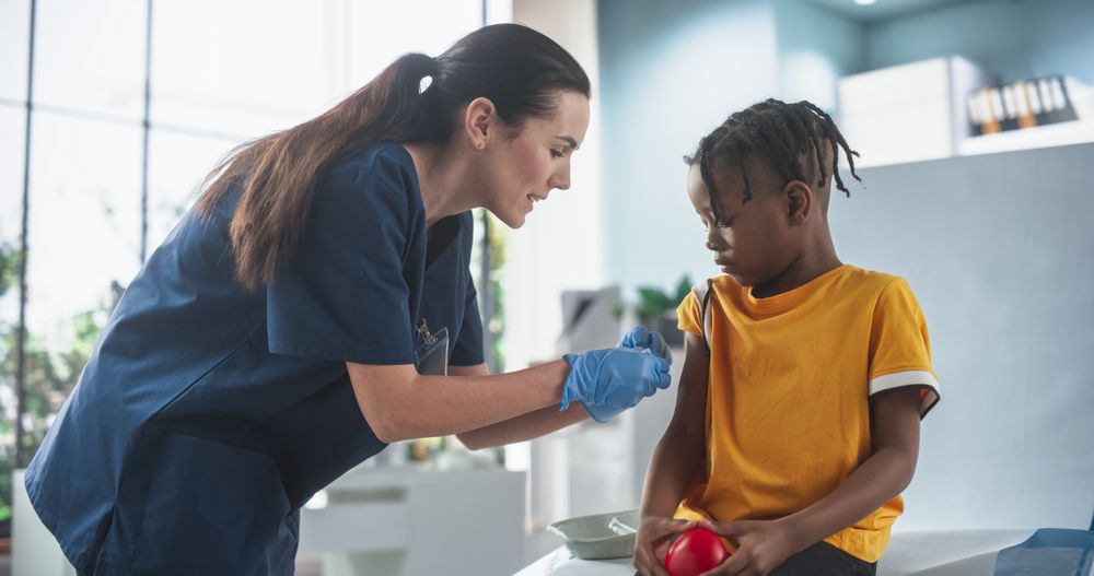 Boy Sitting In The Chair In Bright Hospital And Getting Flu Vaccine.