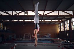 Young male gymnast doing exercises on the parallel apparatus.