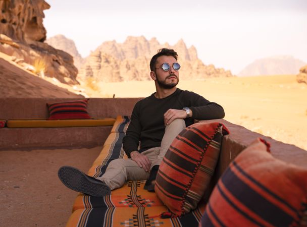Man sitting on cushion in desert