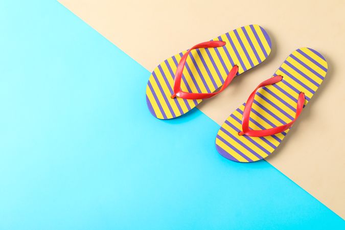 Flip flops on two tone background, space for text and top view. Summer vacation backdrop