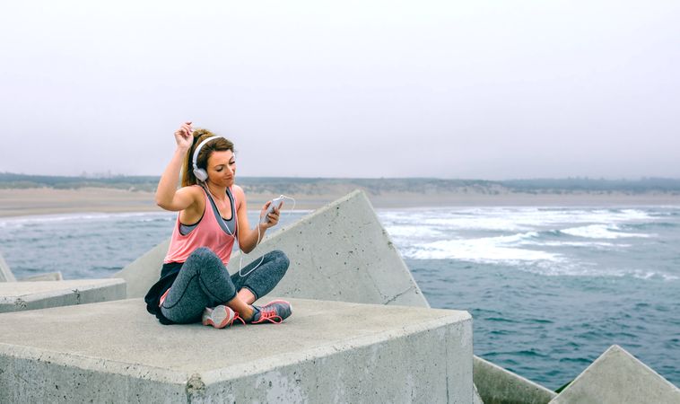 Sportswoman with headphones sitting and dancing